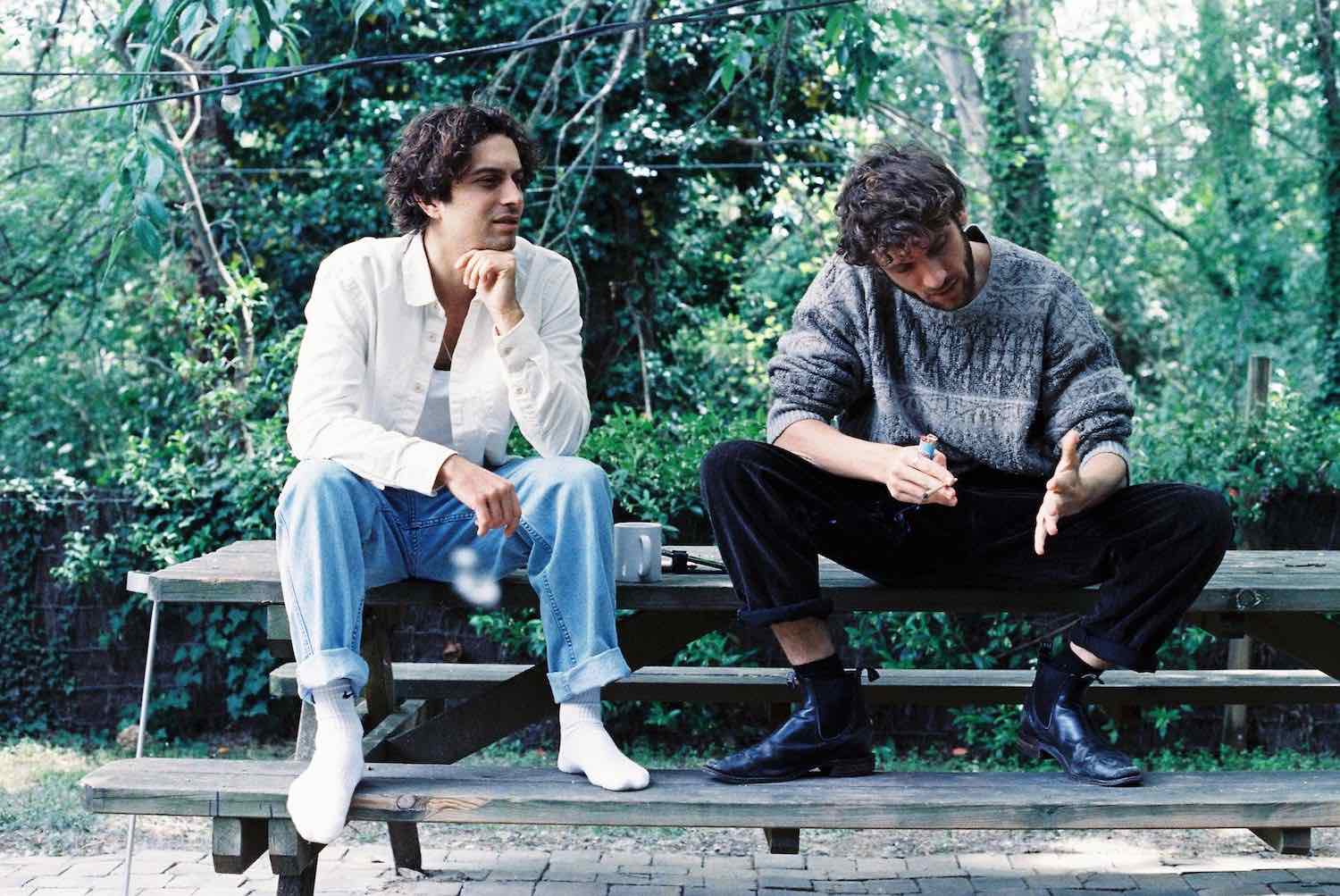 Two members sitting on a wooden bench in dense green woodland