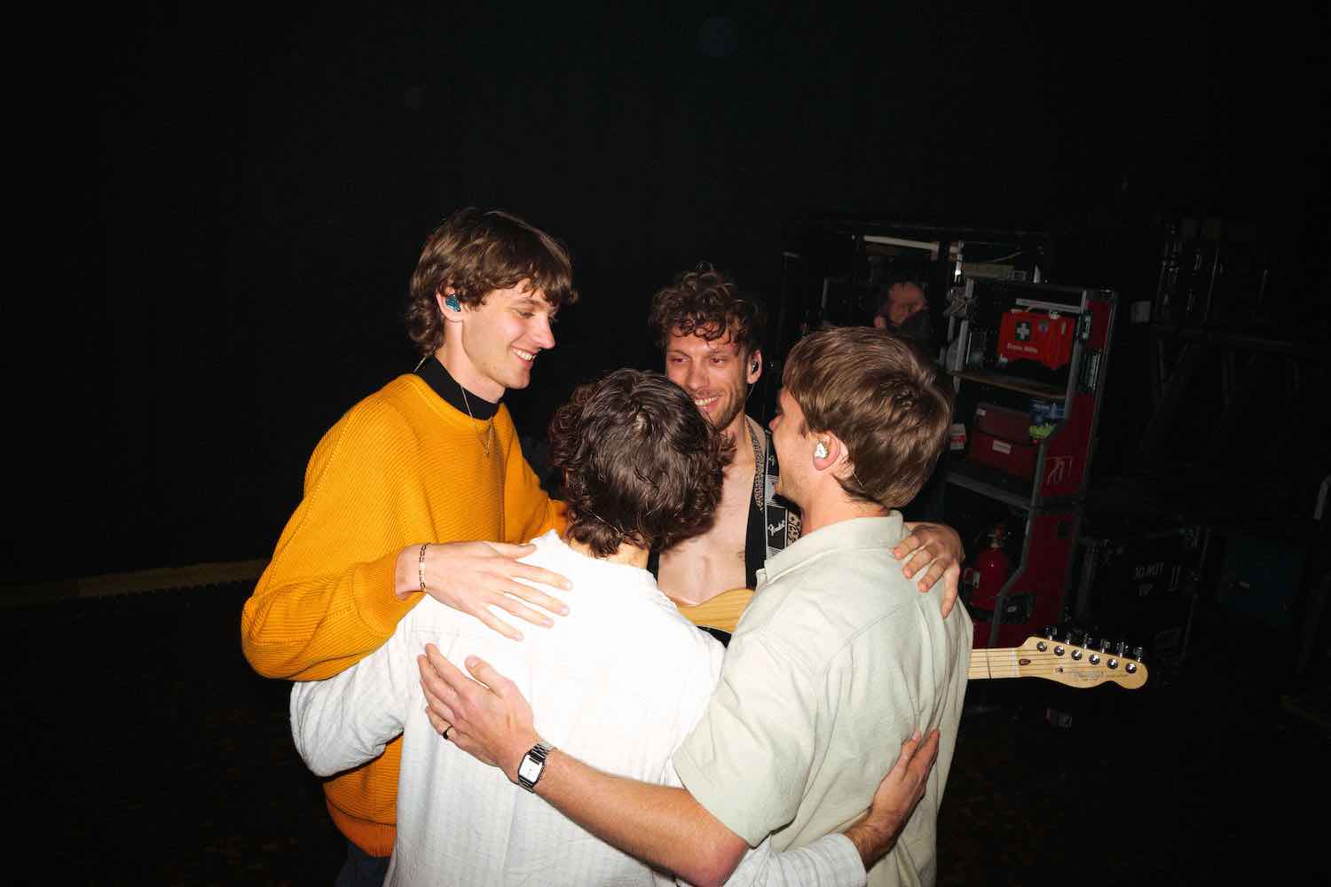 The band in a group embrace backstage