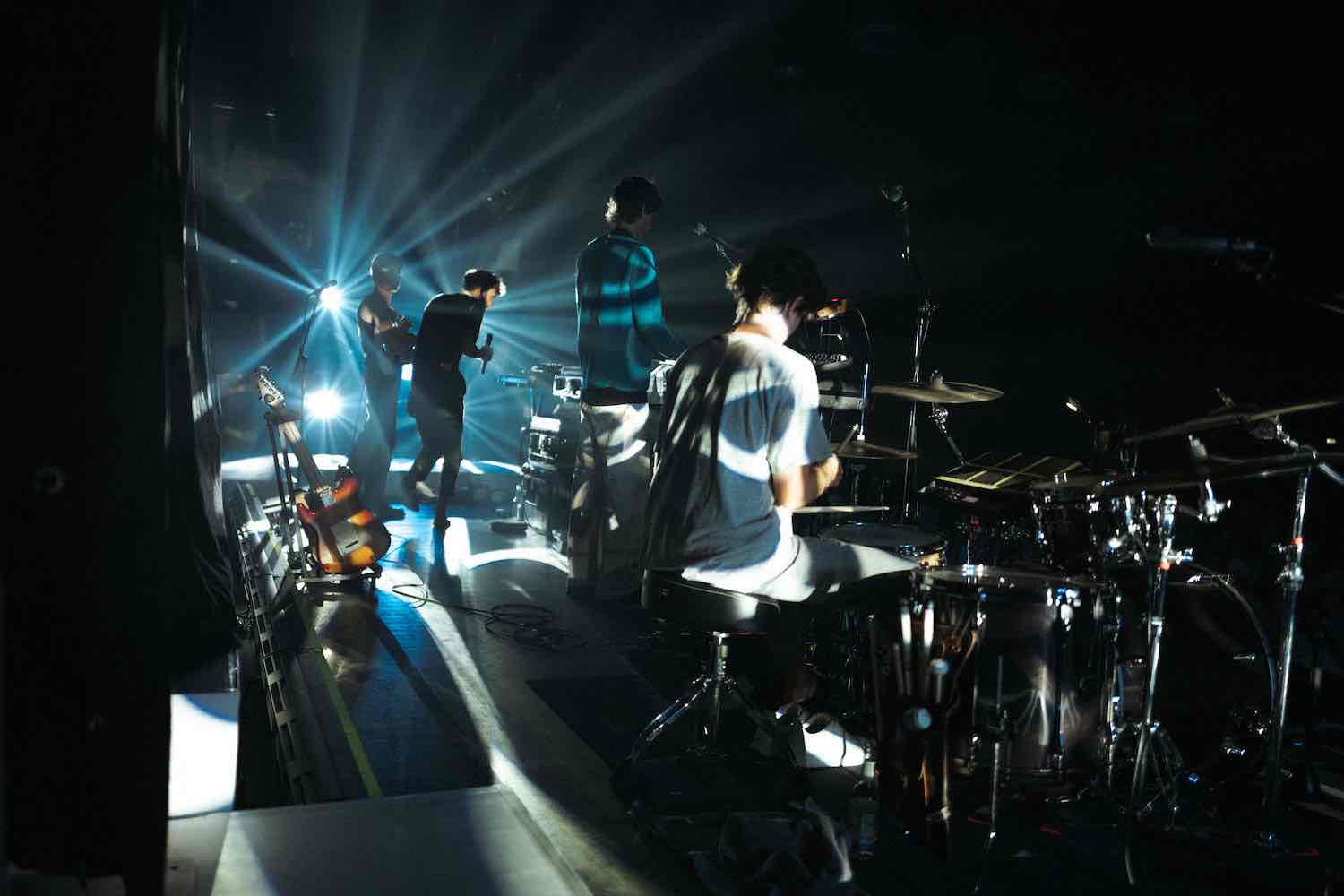 The band playing a darkened stage, cut through by white spotlights