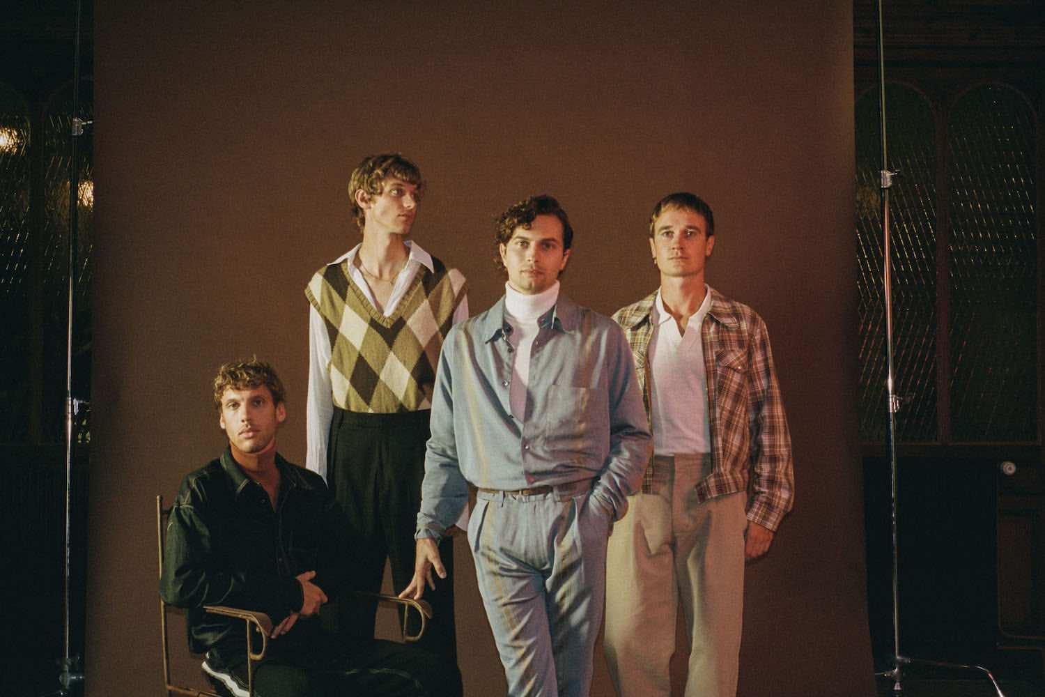 The four members posed together in a warmly lit room