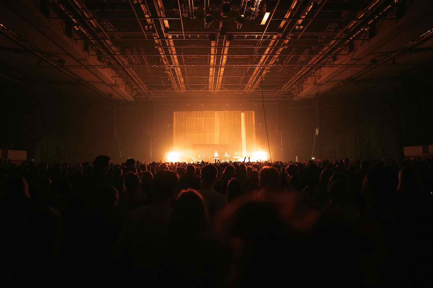 The silhouetted crowd at a TORA show facing a brightly lit stage