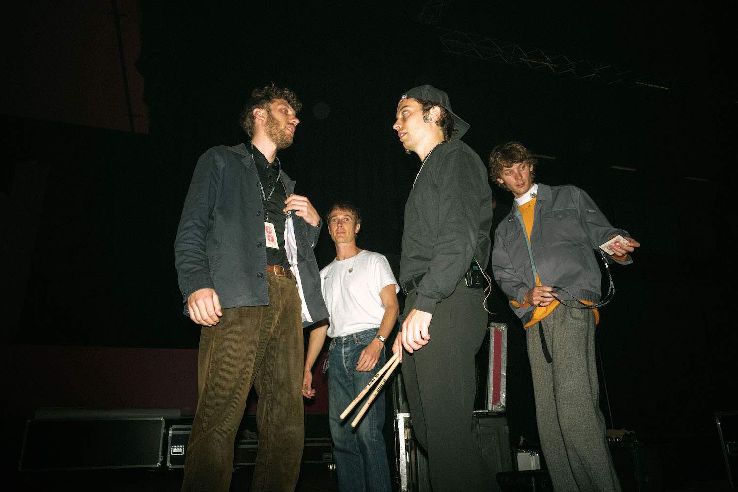 The four members standing together in low light